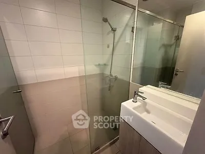Modern bathroom with glass shower and sleek sink in contemporary apartment.