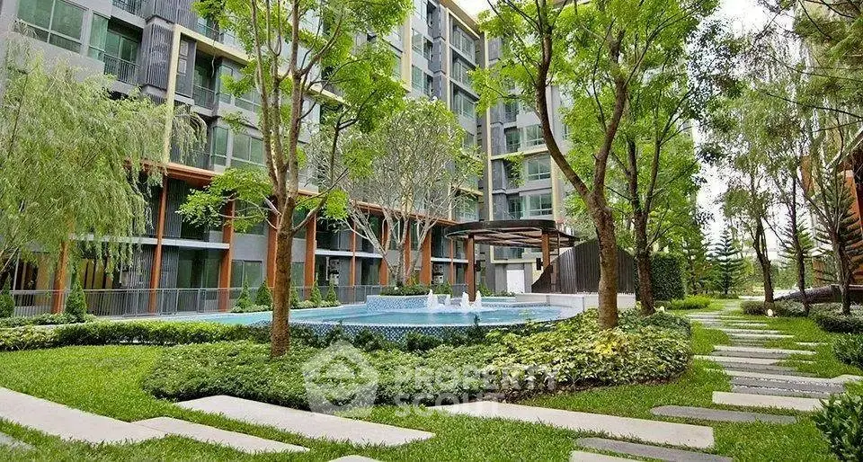 Luxurious residential building with lush garden and serene pool view.