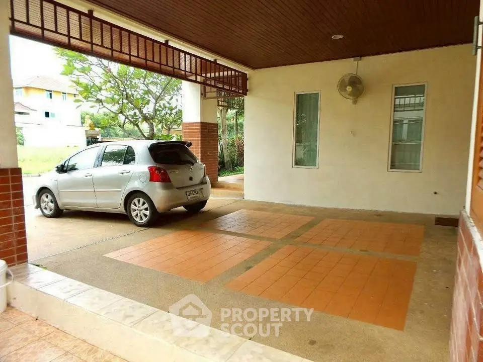 Spacious covered parking area with tiled flooring and ceiling fan in suburban home.