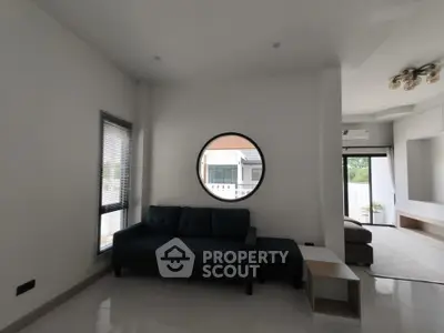 Modern living room with stylish round window and sleek furniture