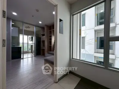 Modern apartment interior with open layout and large windows offering natural light and city views.