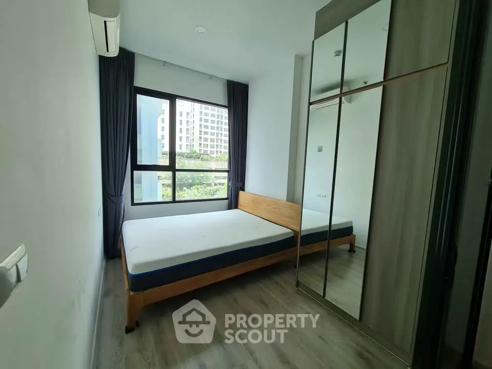 Modern bedroom with large window and mirrored wardrobe in urban apartment