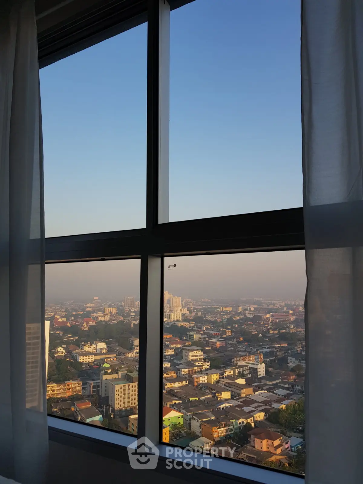 Stunning cityscape view from a high-rise apartment window at sunrise, showcasing urban living.