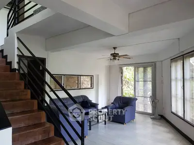 Spacious living room with modern staircase and cozy seating area, perfect for family gatherings.