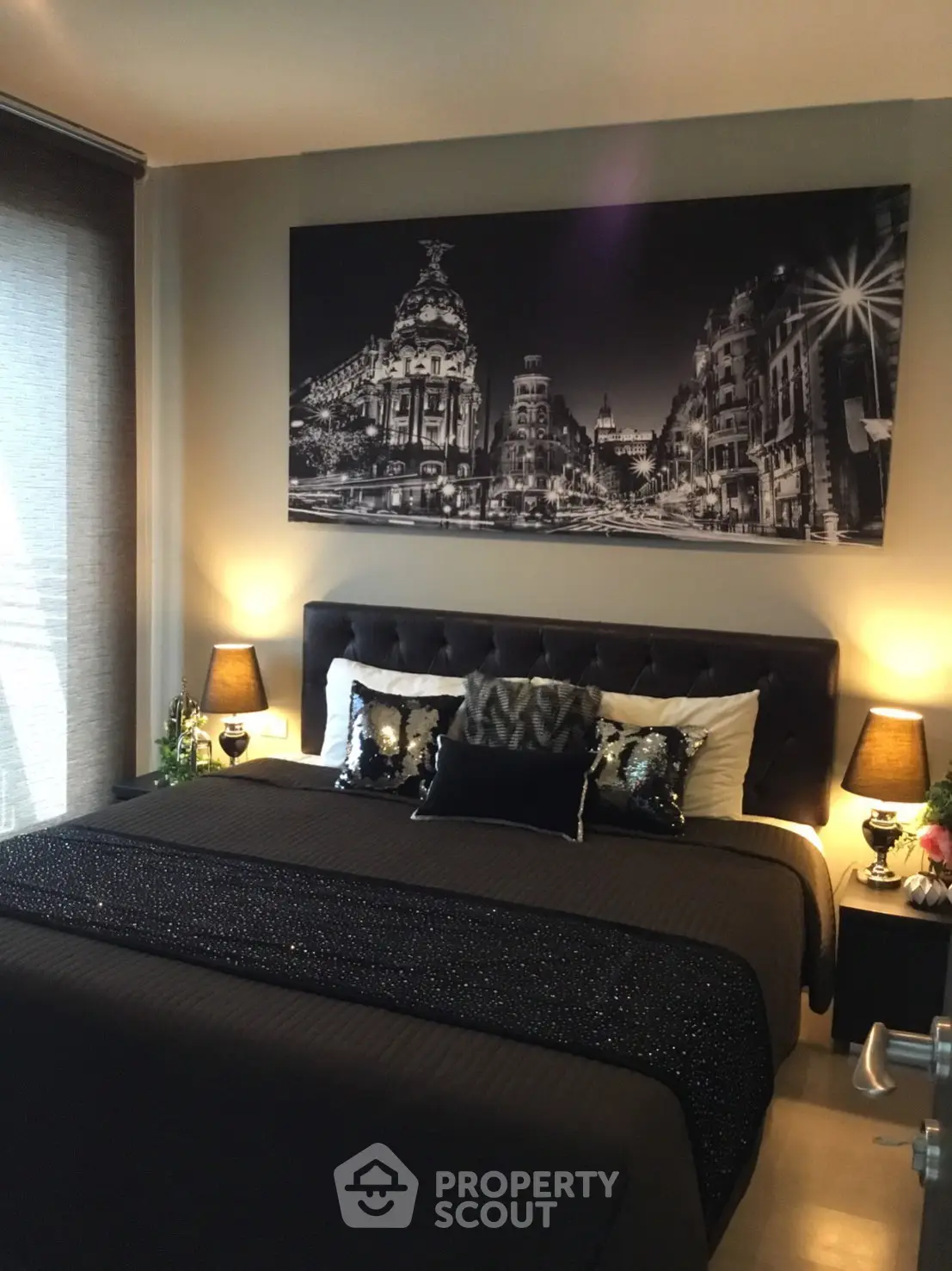 Luxurious bedroom with elegant decor and cityscape artwork above a plush bed, creating a sophisticated ambiance.