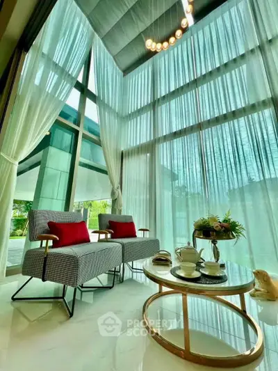 Luxurious living room with high ceilings and elegant decor, featuring floor-to-ceiling windows and modern furniture.