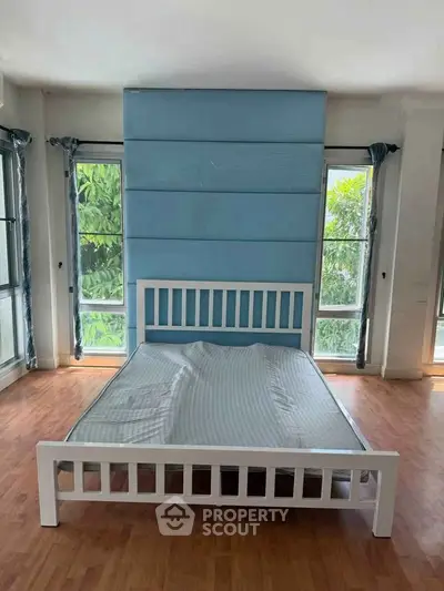 Spacious bedroom with large windows and wooden flooring
