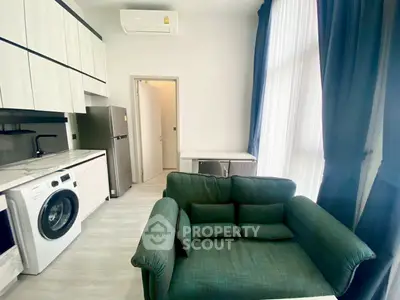 Modern apartment interior with compact kitchen and cozy living area featuring a washing machine and stylish decor.