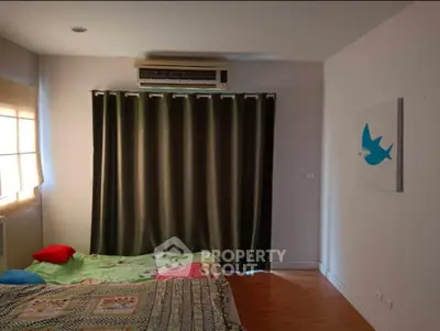 Cozy bedroom with colorful bedding and wall art, featuring air conditioning and natural light.