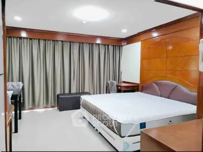 Spacious bedroom with elegant wood paneling and large window drapes, ideal for comfort and relaxation.