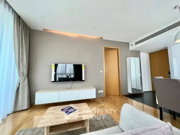 Modern living room with sleek TV setup and stylish furniture in a bright apartment.
