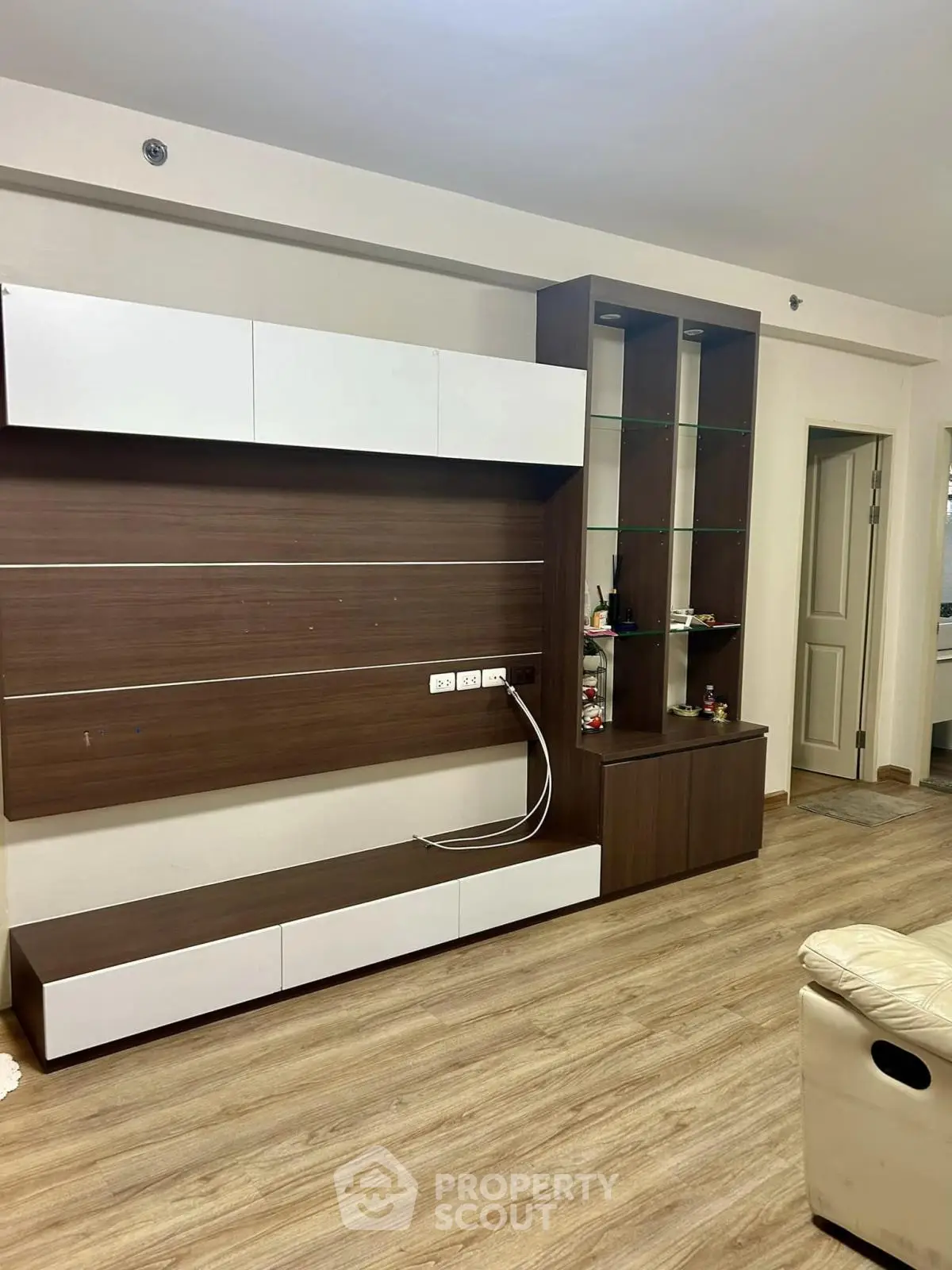 Modern living room with sleek wooden wall unit and glass shelves, perfect for stylish home decor.