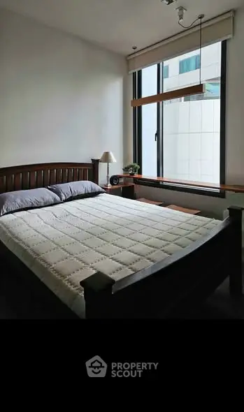 Cozy bedroom with large window and modern furnishings in a stylish apartment.