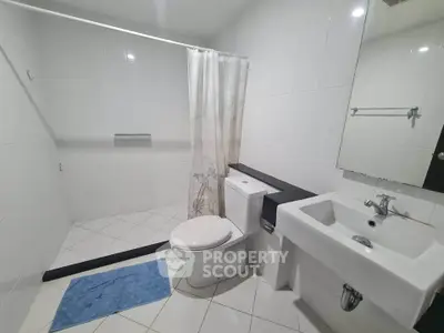 Spacious modern bathroom with sleek white tiles and contemporary fixtures.