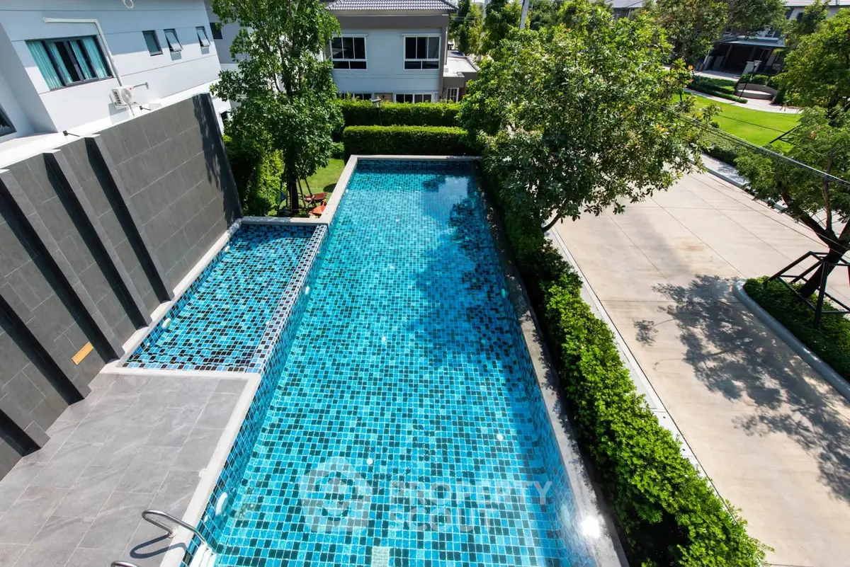 Luxurious residential pool with modern design and lush greenery, perfect for relaxation and leisure.