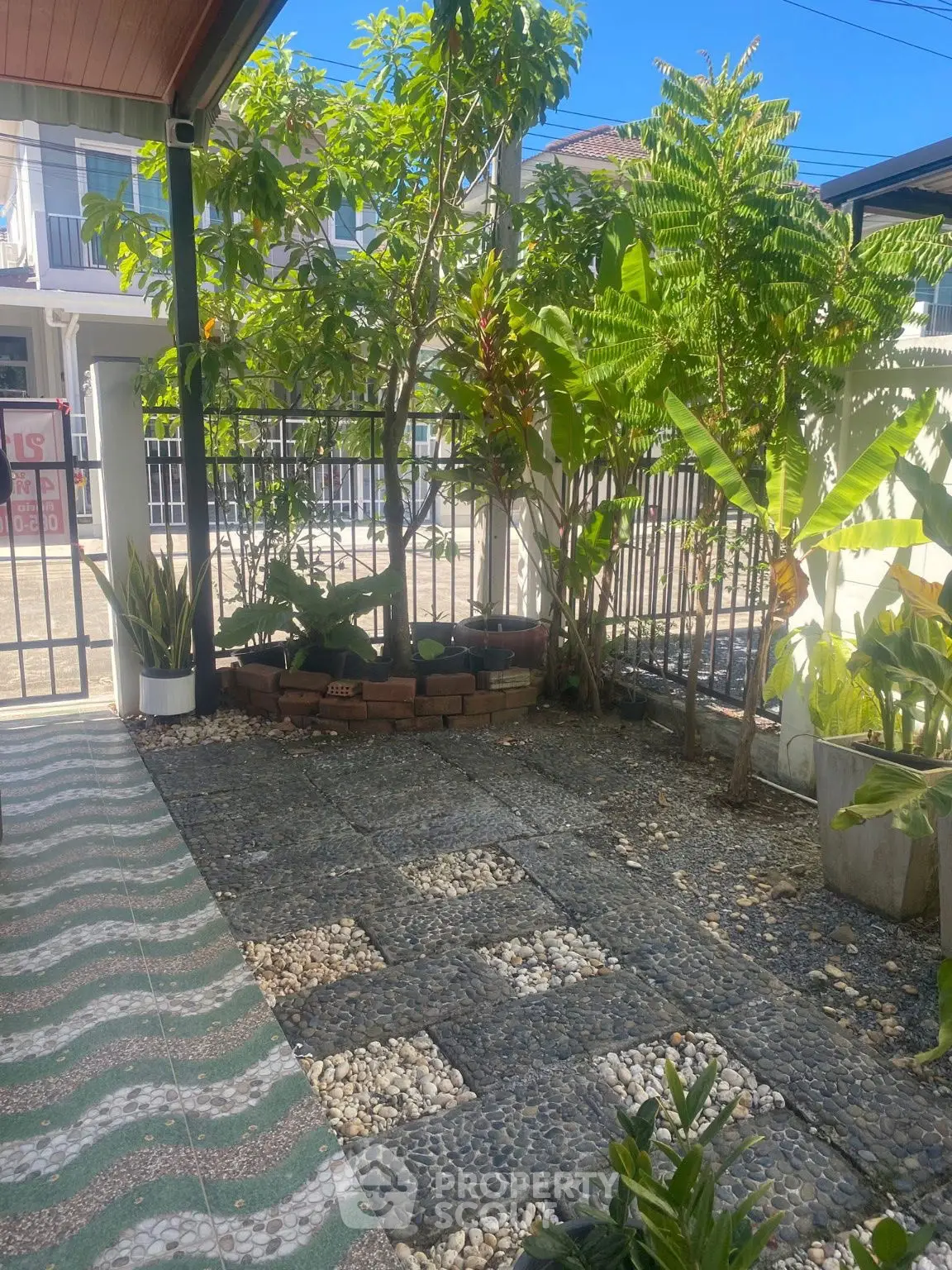 Charming garden area with lush greenery and paved stone pathway in a residential setting.