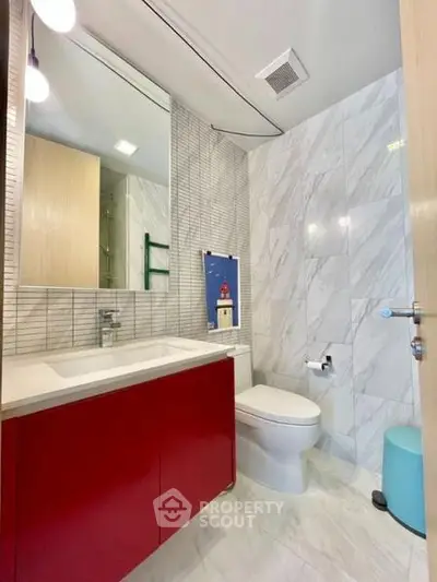 Modern bathroom with red vanity and marble tiles, featuring sleek design and contemporary fixtures.
