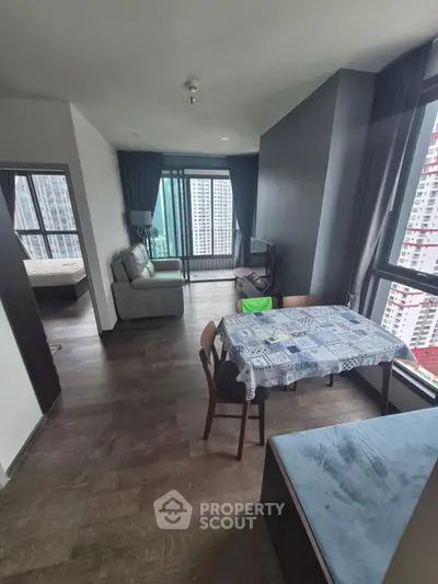 Modern apartment with open living and dining area, featuring large windows and city views.