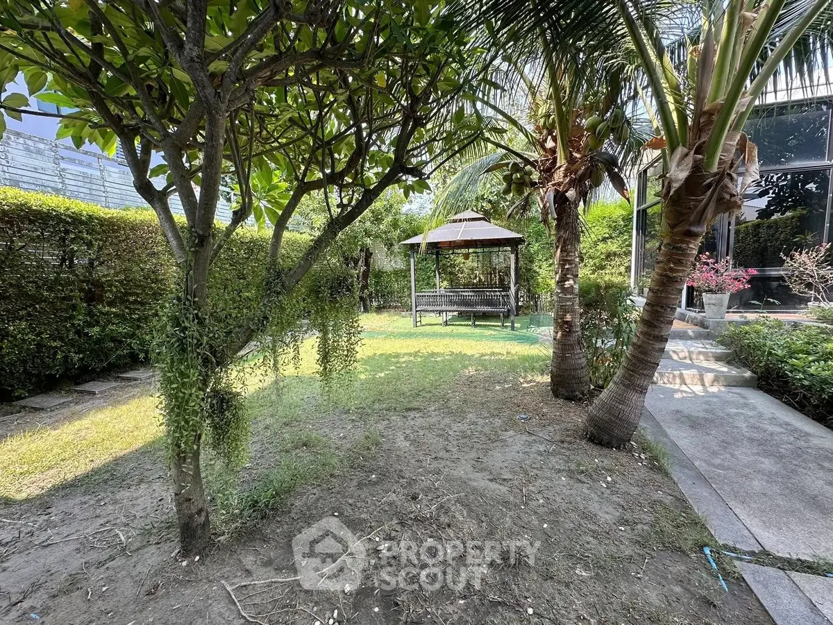 Lush garden with gazebo and palm trees in a serene residential setting.