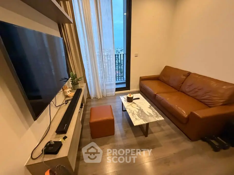 Modern living room with leather sofa, wall-mounted TV, and city view from balcony.