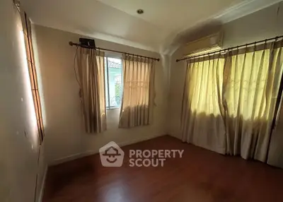 Cozy empty room with wooden flooring and large windows, perfect for a bedroom or study.