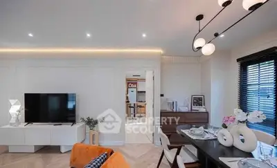 Modern living room with stylish decor and open layout, featuring a sleek TV setup and elegant dining area.