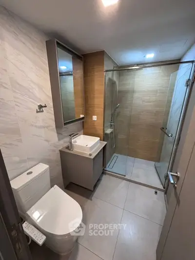 Modern bathroom with sleek design, featuring a glass shower enclosure and contemporary fixtures.