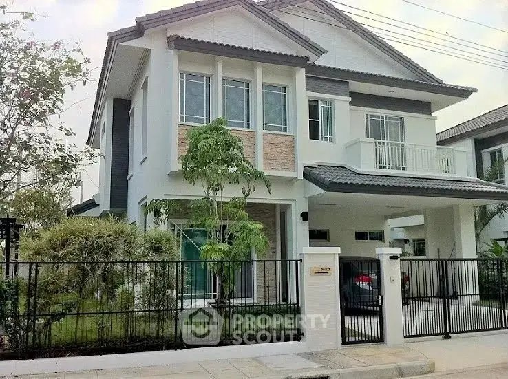 Modern two-story house with a spacious garden and secure fencing in a suburban neighborhood.