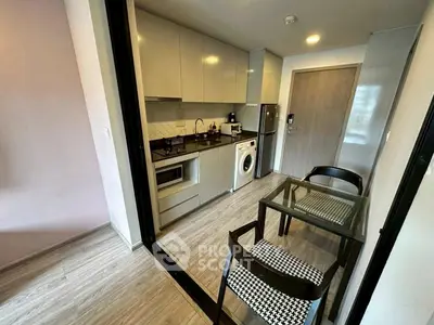 Modern compact kitchen with washing machine and dining area in stylish apartment.