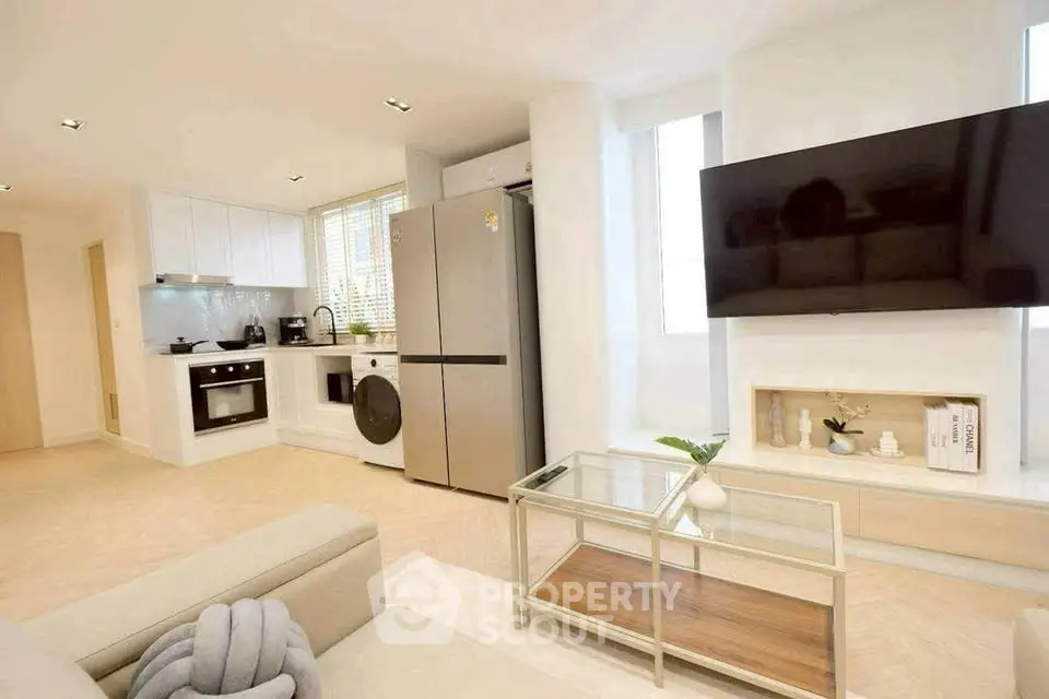 Modern living room with open kitchen, sleek appliances, and stylish decor in a bright apartment.