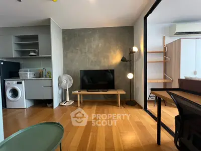 Modern living room with wooden flooring, TV, and washing machine in open layout.