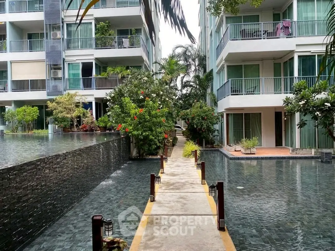 Modern apartment complex with lush greenery and water feature, offering serene living environment.