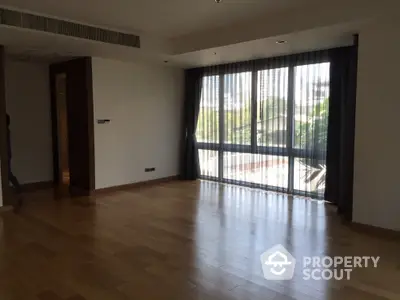 Spacious empty room with large windows and wooden flooring, perfect for customization.