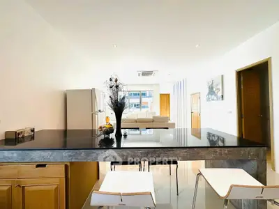 Modern open-plan kitchen with sleek black countertop and stylish dining area in a bright apartment.