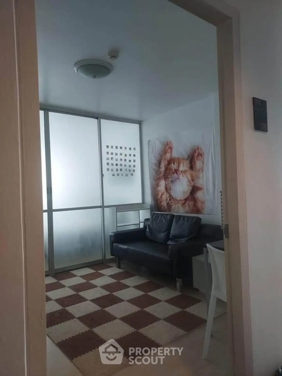 Cozy small living room with modern decor and large cat artwork, perfect for relaxation.