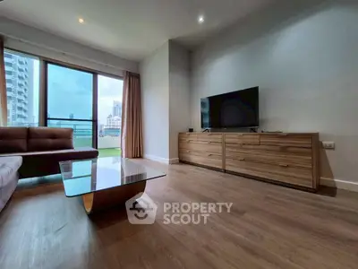 Spacious modern living room with large window and city view, featuring sleek furniture and wooden flooring.