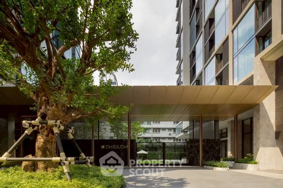 Modern building entrance with lush greenery and sleek architectural design.