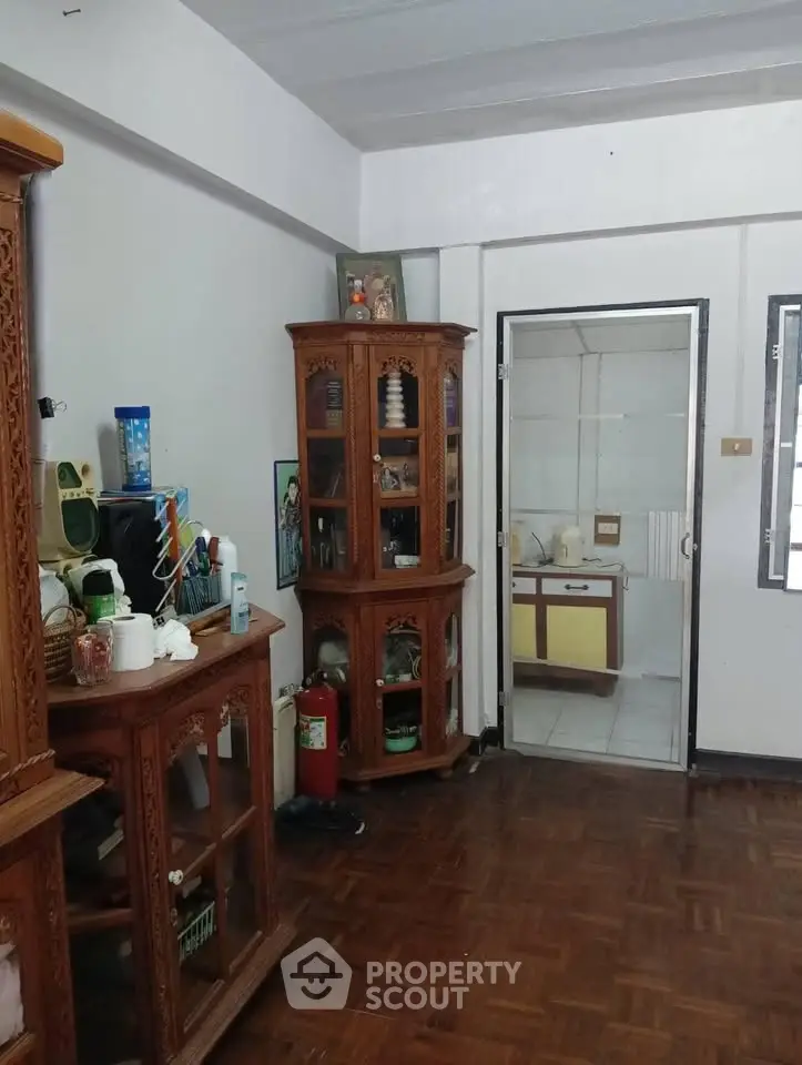 Charming living room with wooden cabinets and parquet flooring, featuring a glass door leading to an adjacent room.