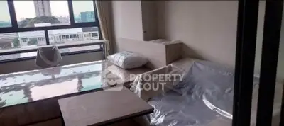 Modern living room with large windows and city view, featuring sleek furniture and natural light.