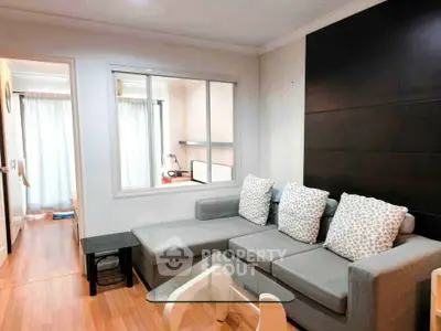 Modern living room with stylish gray sectional sofa and glass coffee table in cozy apartment.