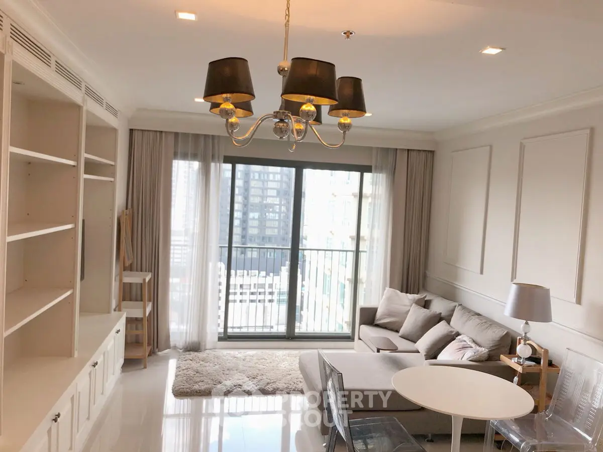 Modern living room with elegant chandelier and city view balcony.