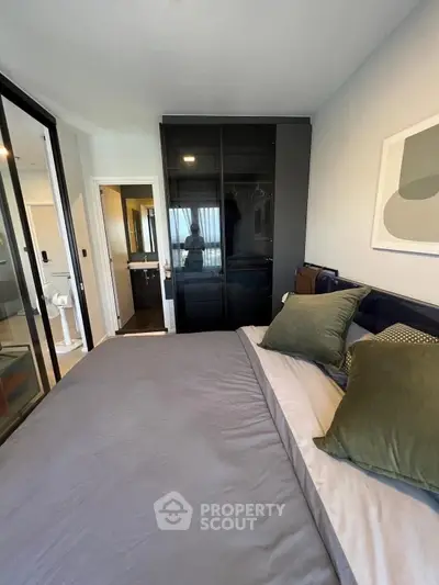 Modern bedroom with sleek design and glass wardrobe doors, featuring a cozy bed and stylish decor.