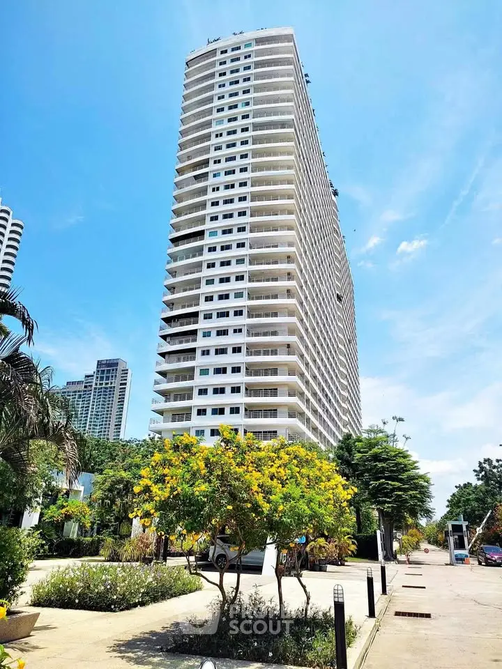 Stunning high-rise building with lush landscaping and clear blue sky, perfect for urban living.