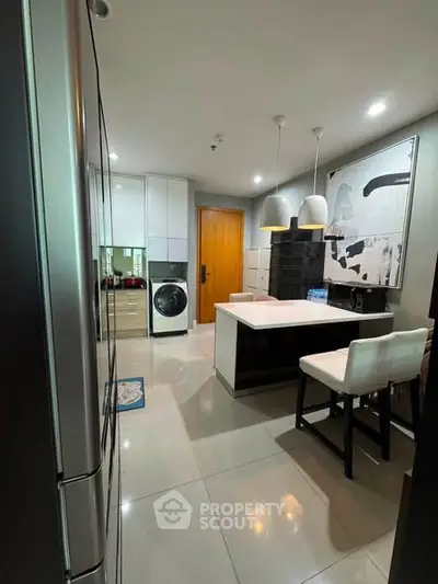 Modern kitchen with sleek design, featuring a washing machine and stylish lighting.