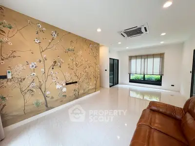 Spacious living room with elegant floral accent wall and modern leather sofa