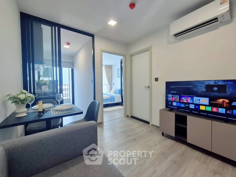 Modern living room with dining area and TV, featuring sleek design and cozy ambiance.