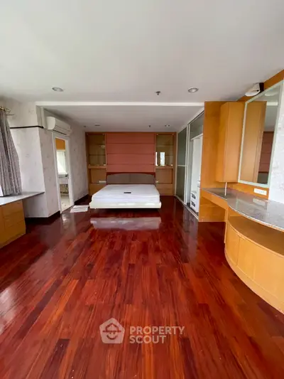 Spacious bedroom with wooden flooring and built-in storage, ideal for modern living.