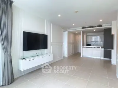 Spacious modern living room with open kitchen and large TV, perfect for contemporary living.