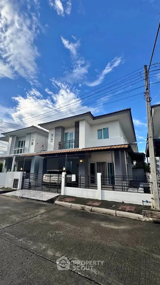 Modern two-story house with sleek design and spacious driveway under a clear blue sky.