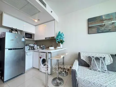 Modern kitchen with sleek appliances and cozy living area in open layout apartment.